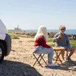 Couple en camping-car stationné sur une plage portugaise, déjeunant en extérieur
