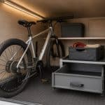Vue intérieure d’une soute de camping-car aménagée avec tiroir coulissant, rails d’arrimage et accessoires de rangement — idée d’aménagement soute camping-car Rapido ou Pilote.