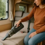 Femme nettoyant la banquette d’un camping-car avec un aspirateur portable sans fil