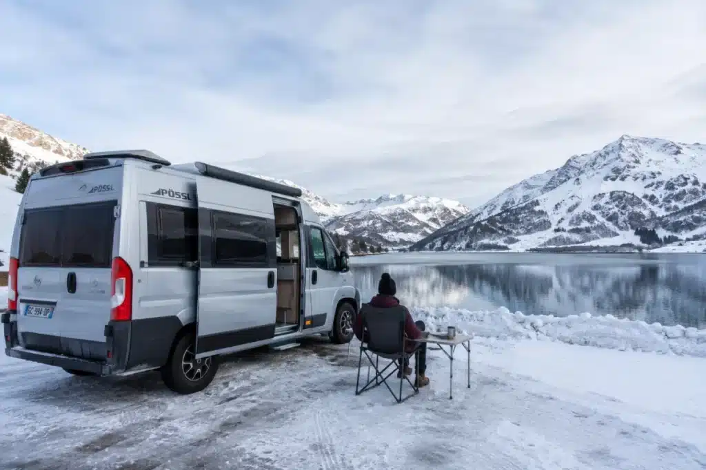 Camping-car aménagé stationné dans un paysage enneigé en montagne, symbole de la vie en camping-car toute l'année.
