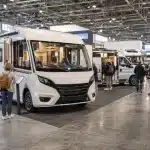 Salon du camping-car Paris-Le Bourget 2026 avec plusieurs véhicules et visiteurs dans le hall d’exposition.